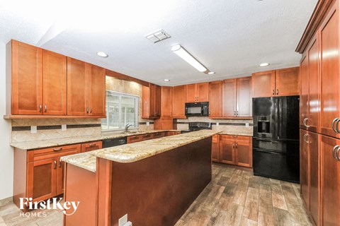 A kitchen with wooden cabinets and a black refrigerator.