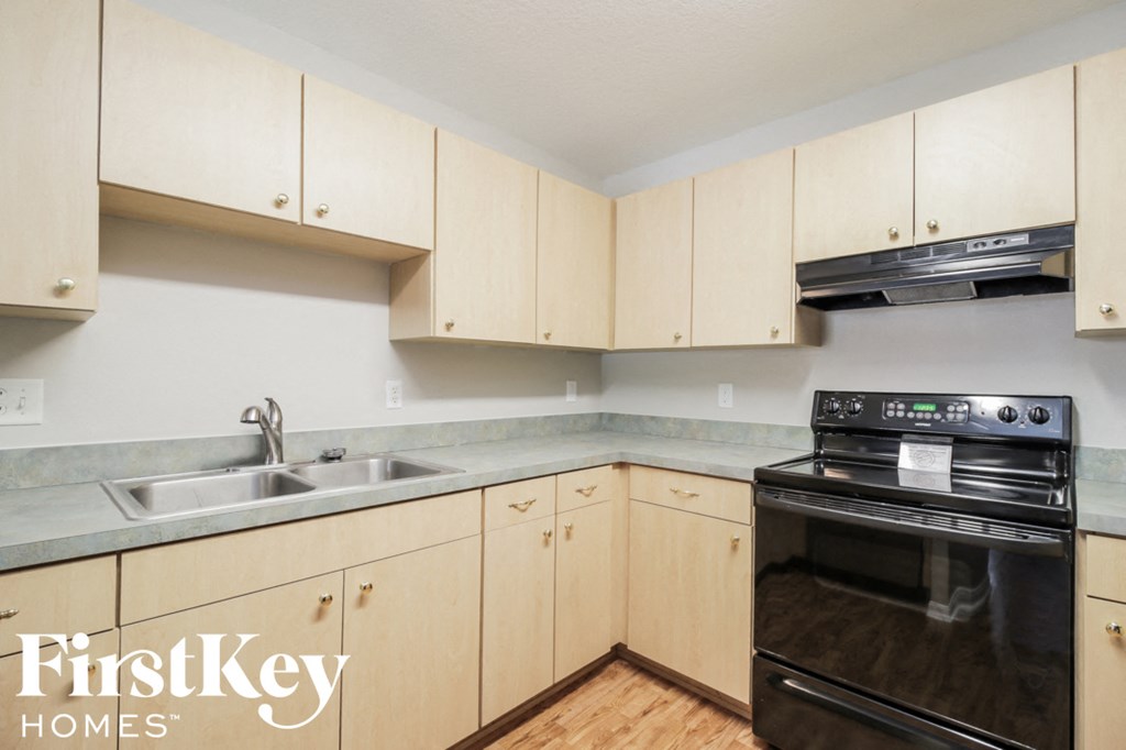 A kitchen with wooden cabinets and a black oven.