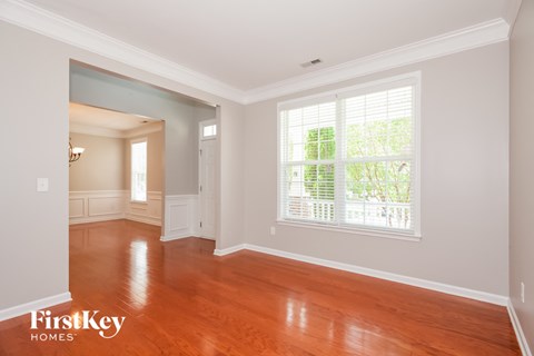 A room with wooden floors and a window with blinds.