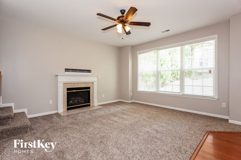 A living room with a fireplace and a ceiling fan.