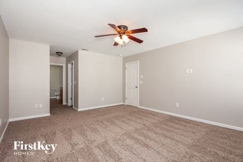 A spacious room with a carpeted floor and a ceiling fan.