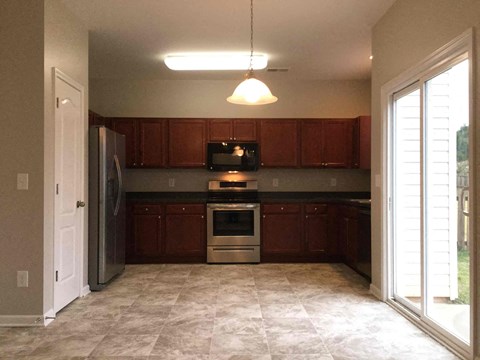 A kitchen with brown cabinets and a tiled floor.
