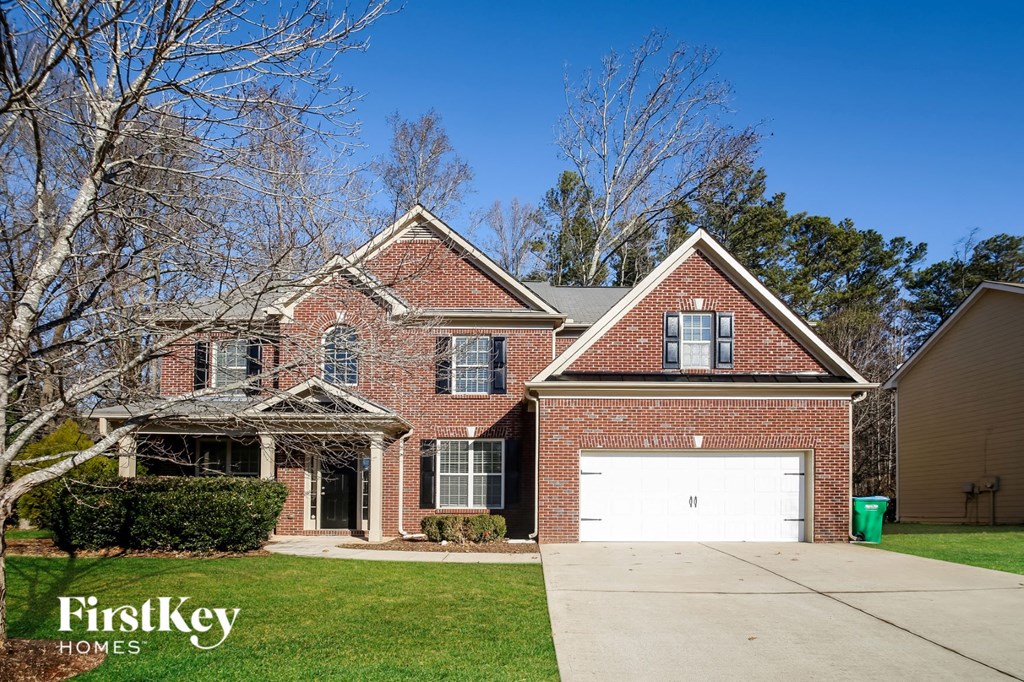 A brick house with a garage and a tree in front.