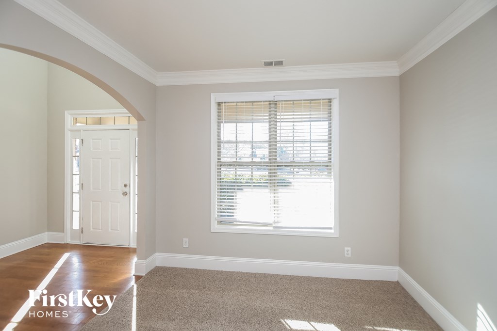 A room with a carpeted floor and a window with blinds.