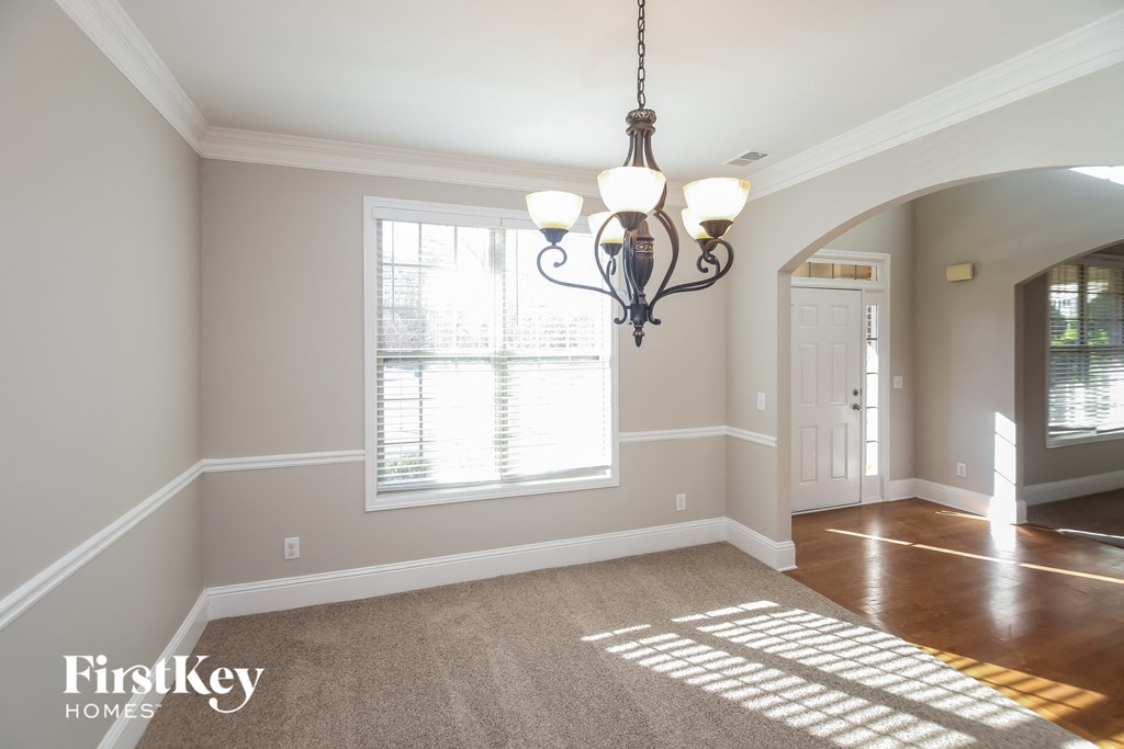 A well-lit room with a chandelier and a carpet on the floor.