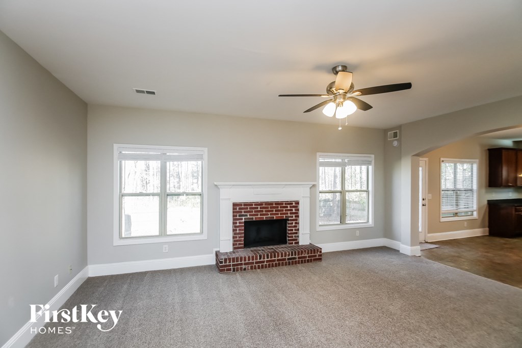 A living room with a fireplace and a ceiling fan.