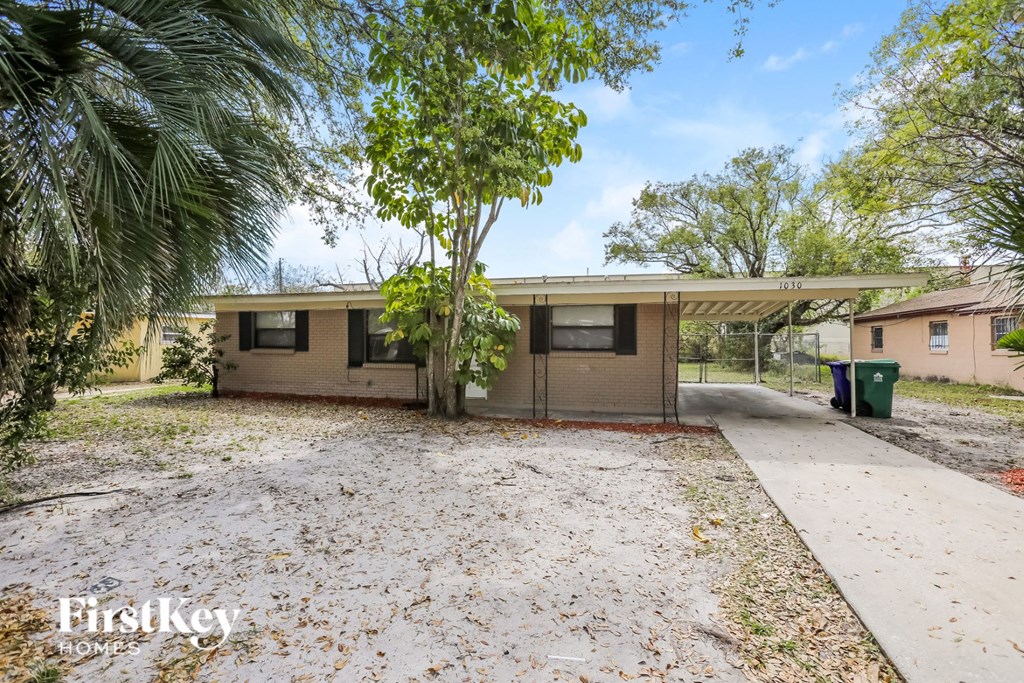 a small house with a driveway and a palm tree
