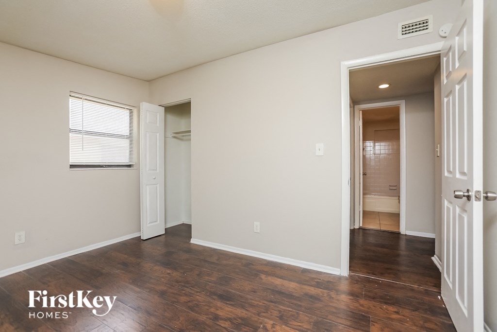 an empty living room with a door to a hallway and a bathroom