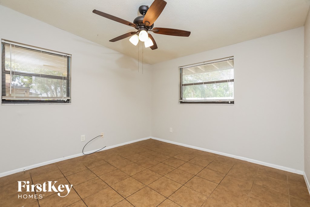 a living room with a ceiling fan and a tiled floor