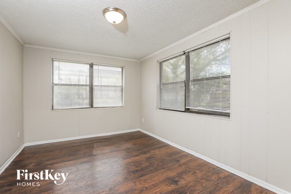 the living room of an empty house with wood floors and two windows