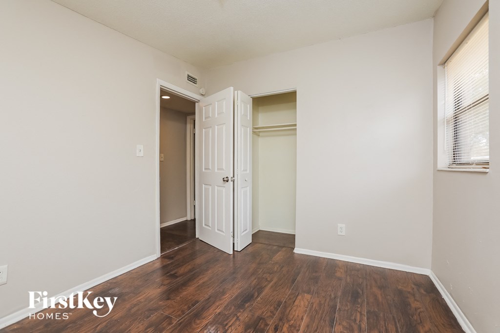 a living room with wood flooring and white walls and a closet