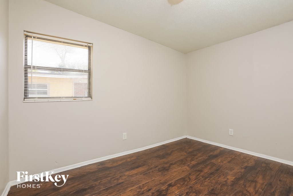 a bedroom with wood flooring and a window