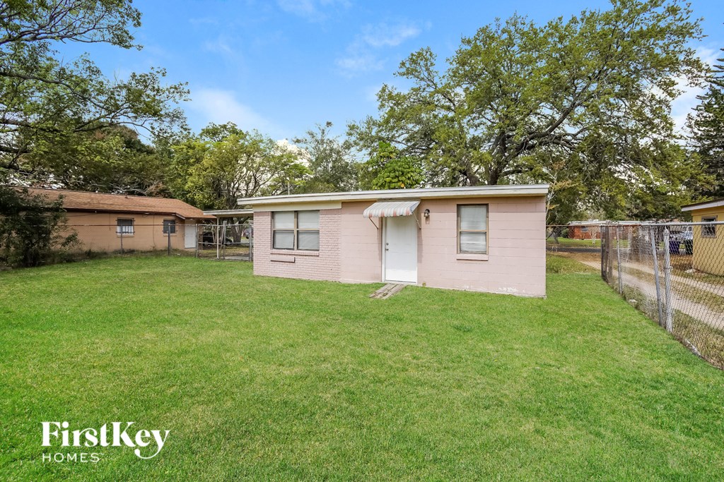 a small pink house with a yard and a fence
