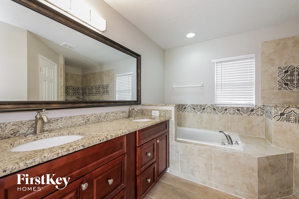 a bathroom with two sinks and a tub and a mirror