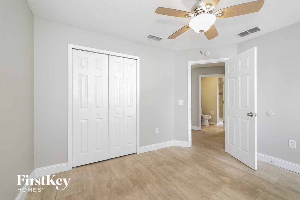 a bedroom with a ceiling fan and a door to a bathroom
