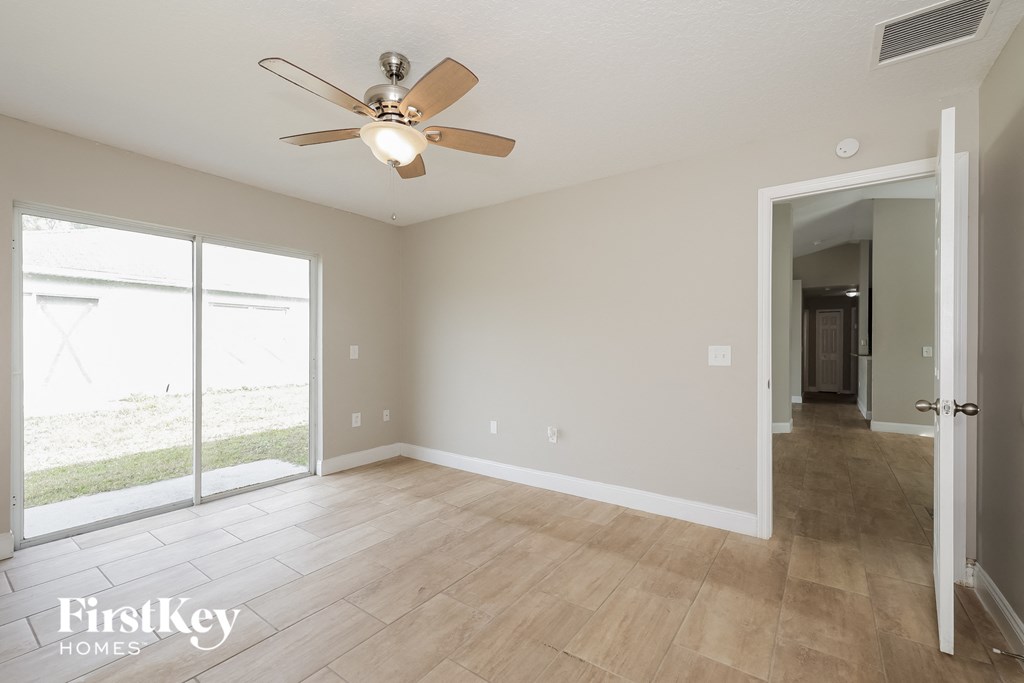 an empty living room with a ceiling fan and a large window