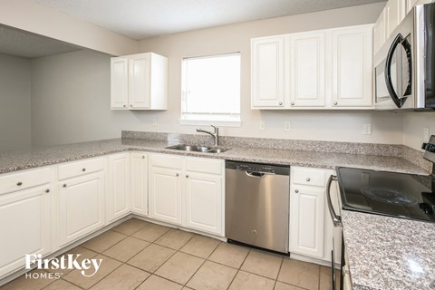 A kitchen with white cabinets and a granite countertop.