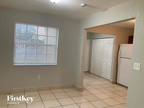 A kitchen area with a white refrigerator and a window with blinds.