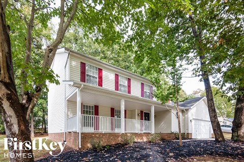 a white house with red shutters and a tree in front of it