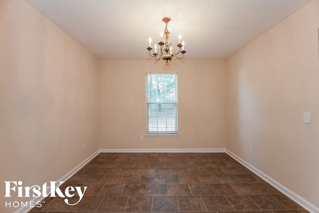 a empty dining room with tile floors and a chandelier