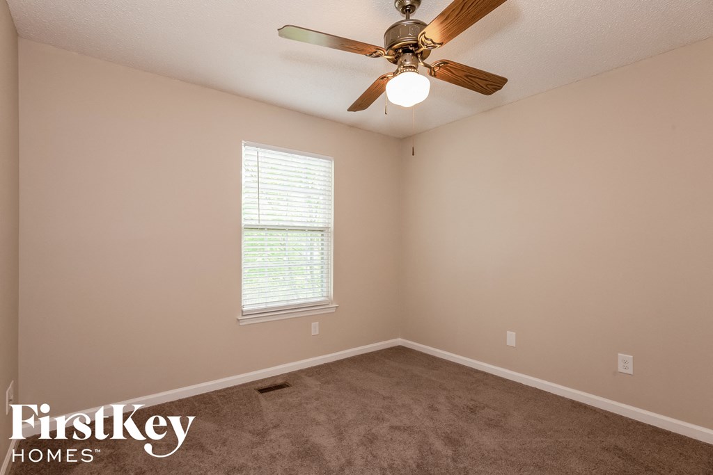 a carpeted room with a ceiling fan and a window