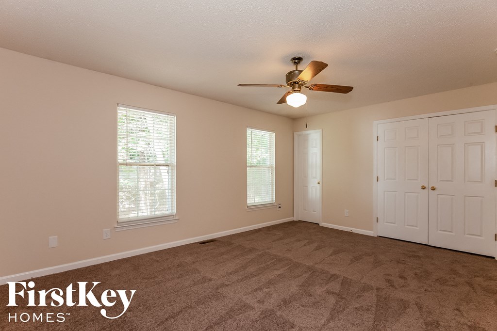 a living room with carpet and a ceiling fan