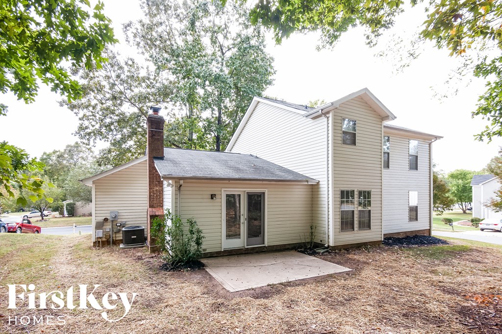 the front of a white house with a yard and trees