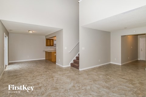 an empty living room with a staircase and a kitchen