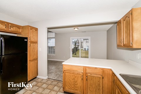 an empty kitchen with wooden cabinets and a black refrigerator