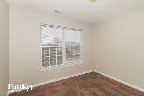 a bedroom with a large window and a brown carpet