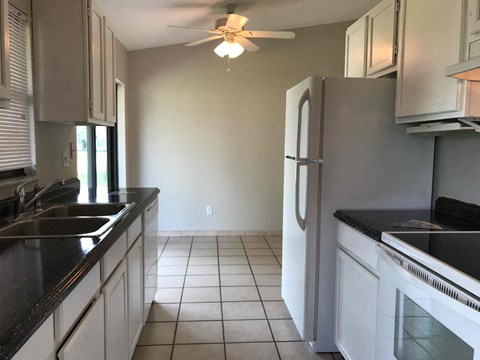 A kitchen with white cabinets and black countertops.