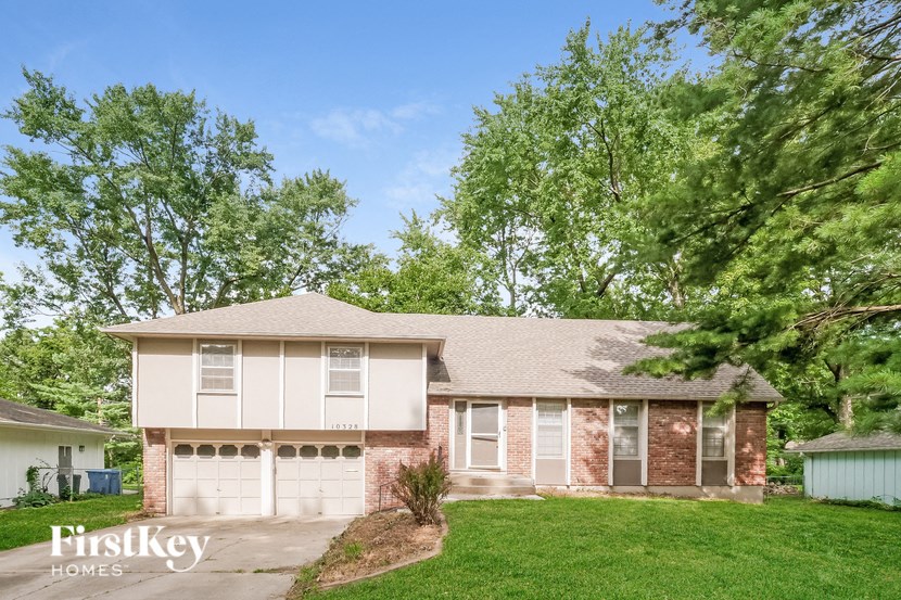 a brick house with white garage doors and a green lawn