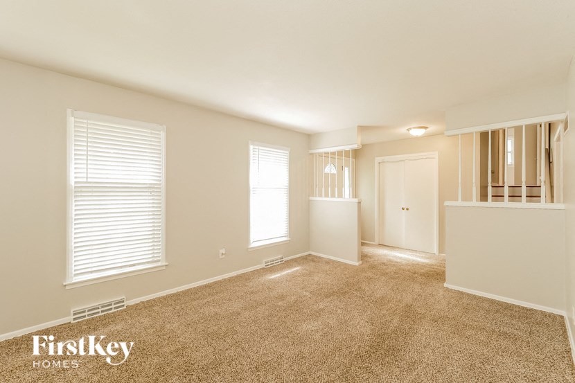an empty living room with carpet and a door to a staircase