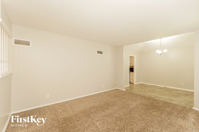 an empty living room with a carpeted floor and white walls