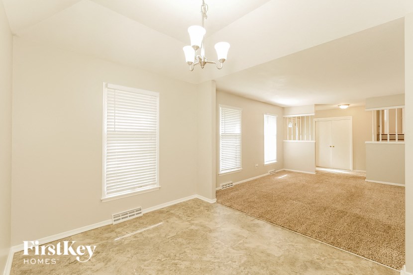 a empty living room with a rug and a chandelier