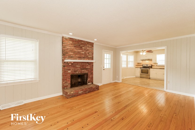 a living room with a brick fireplace and a wooden floor