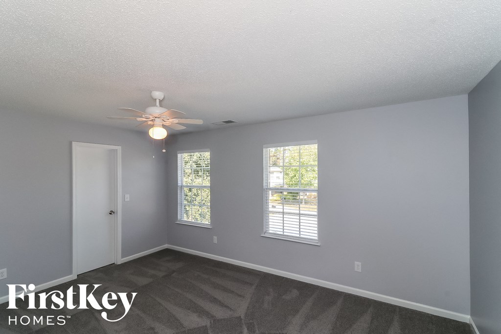 a bedroom with a ceiling fan and two windows