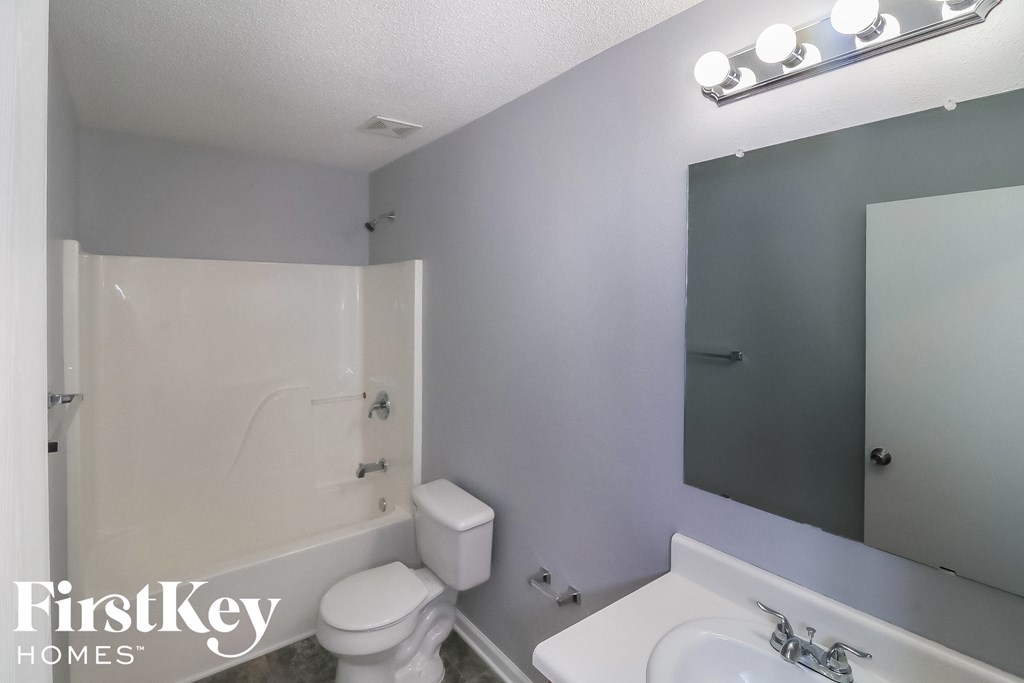a white bathroom with a white toilet and a sink and a shower