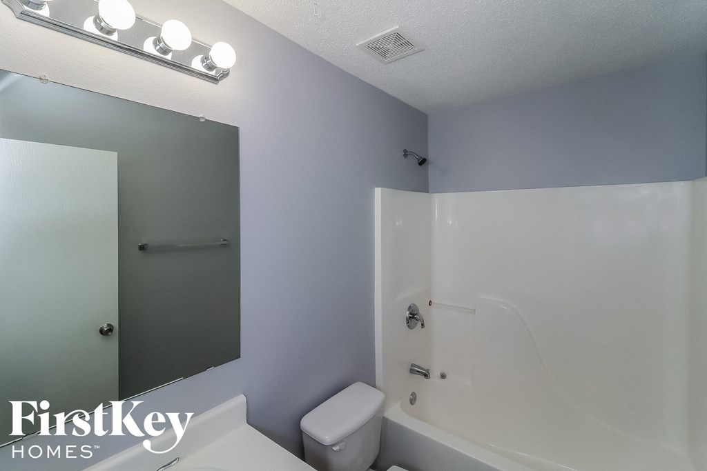 a white bathroom with a tub and a sink and a mirror