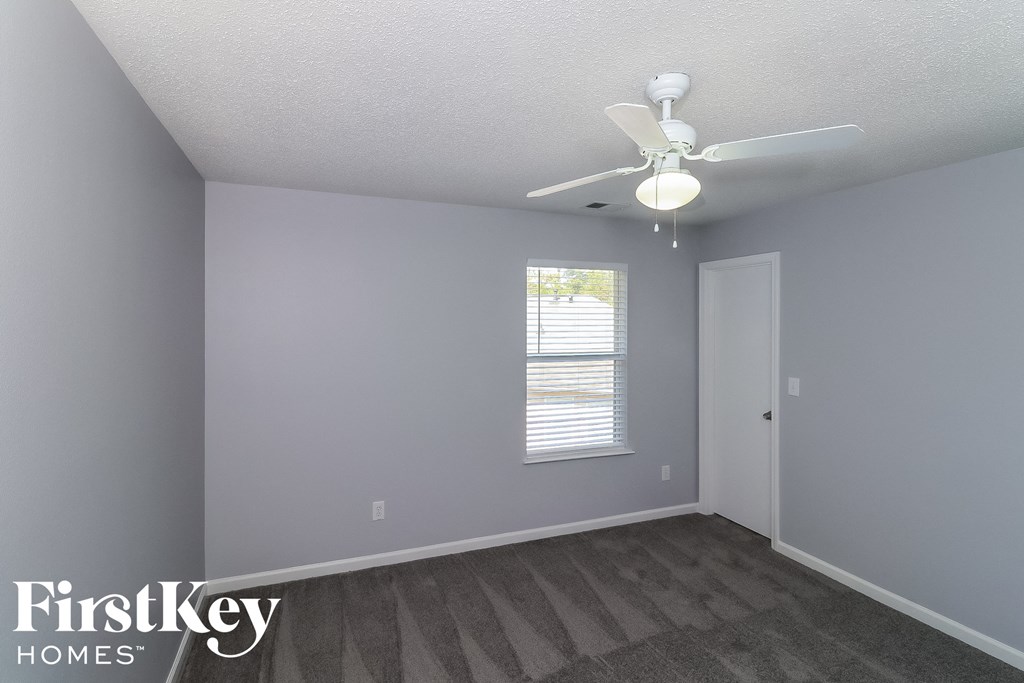 a bedroom with gray walls and a ceiling fan