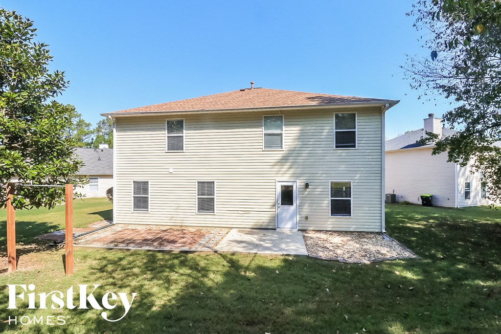 the back of a white house with a yard and a driveway