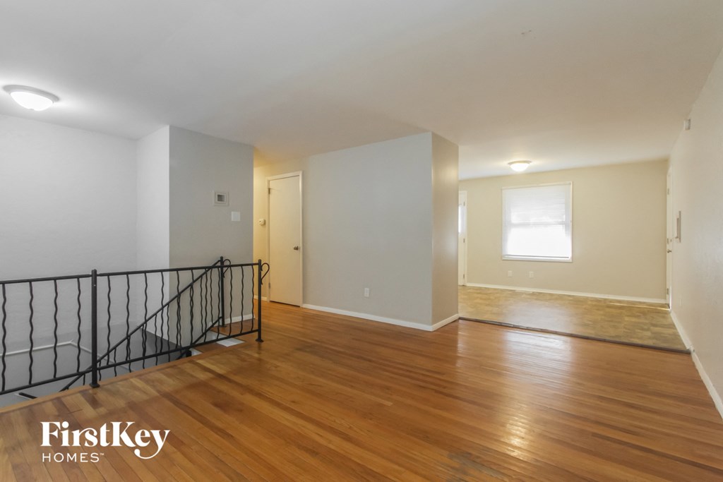 the living room and dining room of an empty home with wood floors and a staircase