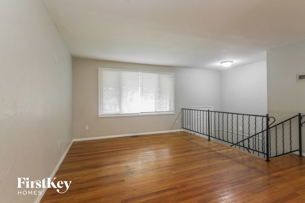 an empty living room with a wood floor and a window