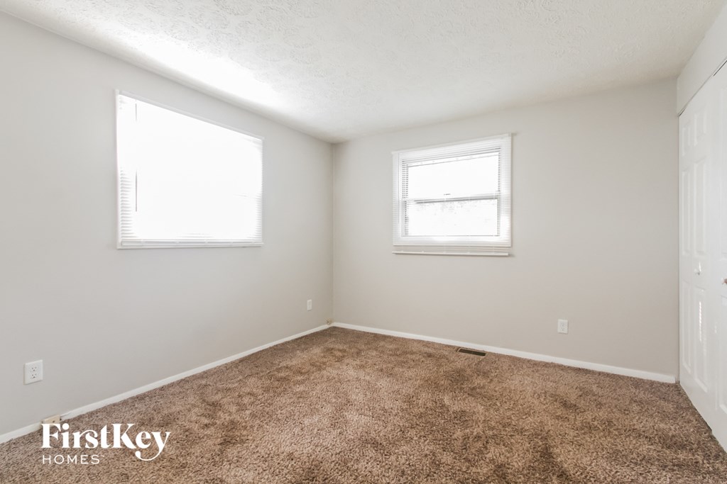 a bedroom with a carpeted floor and two windows