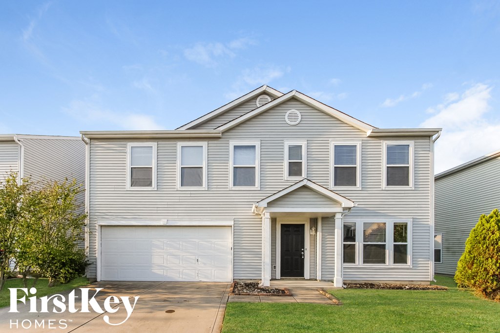 a white house with a garage door and a lawn