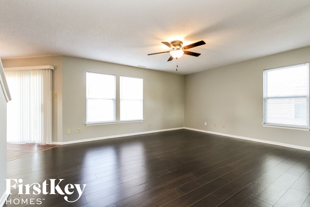 an empty living room with wood floors and a ceiling fan