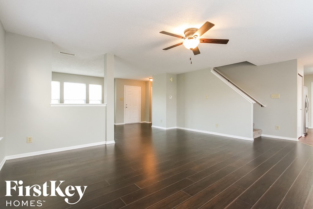 an empty living room with wood floors and a ceiling fan