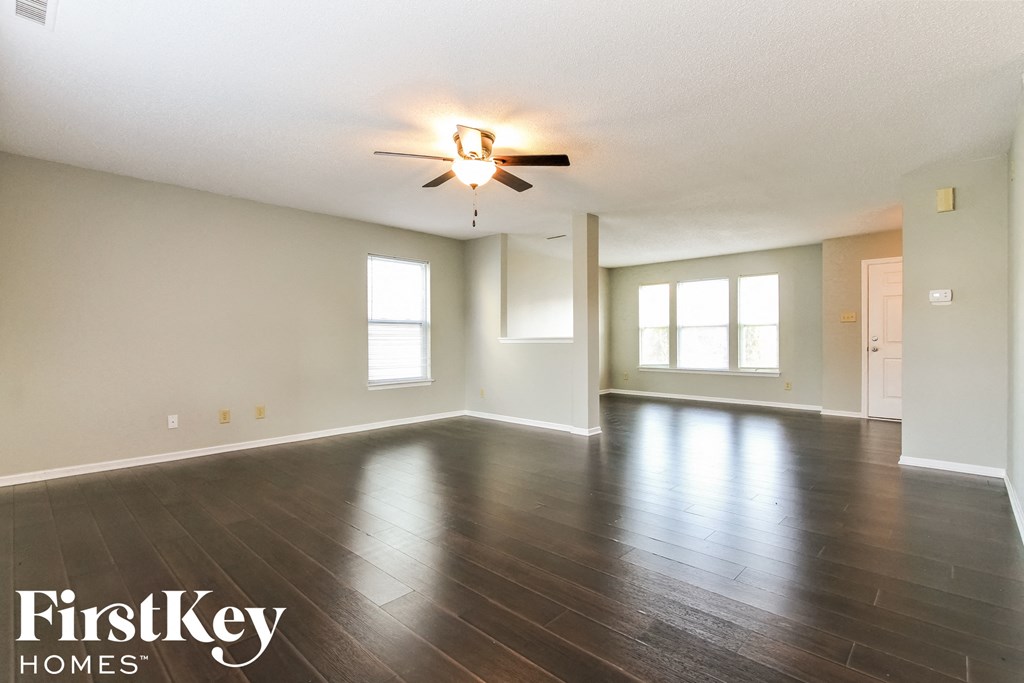 an empty living room with wood floors and a ceiling fan