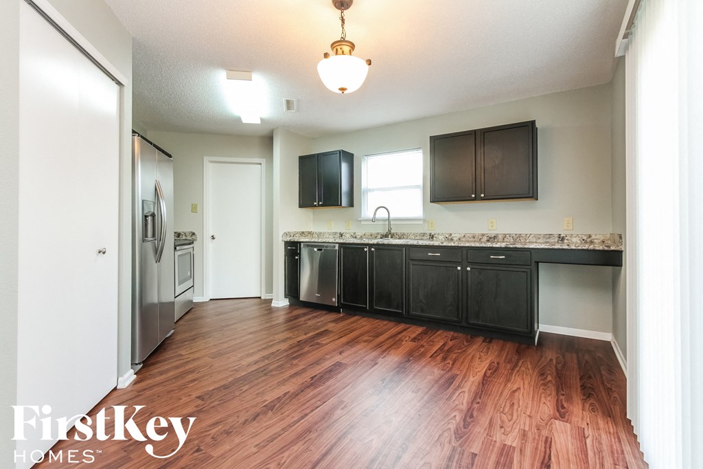 a kitchen with wood flooring and stainless steel appliances