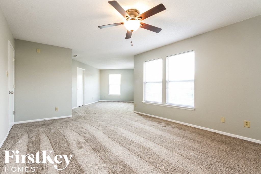 the living room and dining room with carpet and a ceiling fan